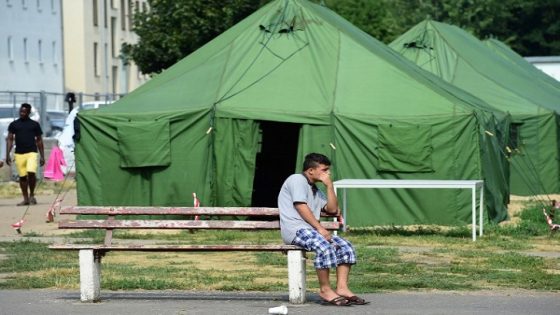 An asylum seeker sits in front of tents at the centre for asylum seekers "Zentrale Aufnahmestelle für Asylbewerber", in Eisenhuettenstadt, eastern Germany, near the Polish border, on August 13, 2015. Germany's interior minister said during his visit in the main communal housing center for the state of Brandenburg it was "unacceptable" that 40 percent of a record wave of asylum-seekers in his country were from the Balkans, as Germany has struggled to accommodate a flood of asylum seekers from war zones such as Syria but also from countries without military conflict in southeastern Europe, including Albania, Serbia and Kosovo. AFP PHOTO / JOHN MACDOUGALL