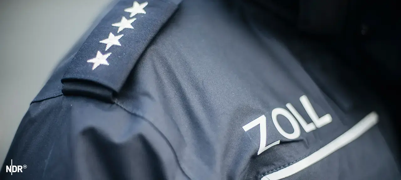 ndr-ueber-der-brusttasche-einer-blauen-uniform-steht-das-wort-zoll-100