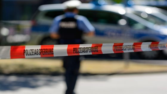 JW29GE Police cordon with barrier tape, at back patrol cars and police officers, Frankfurt am Main, Germany